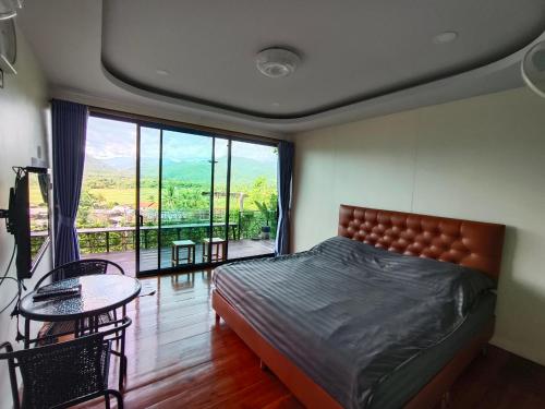 ein Schlafzimmer mit einem Bett, einem Tisch und einem großen Fenster in der Unterkunft นะลาวิว รีสอร์ท ปัว Nala View Resort Pua in Pua