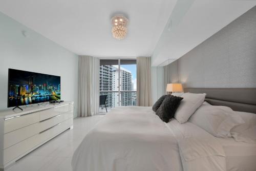 a white bedroom with a large bed and a tv at Perfect One Bedroom at Icon Brickell Amazing views in Miami