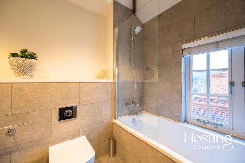 a bathroom with a tub and a toilet and a window at The Penthouse, Henley-On-Thames in Henley on Thames