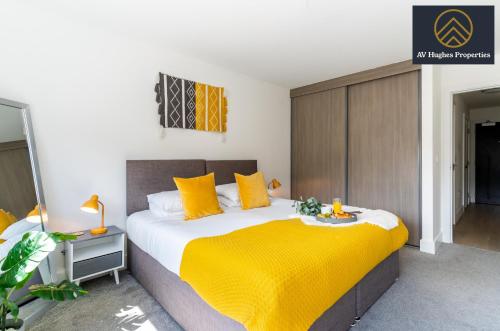 a bedroom with a large bed with yellow pillows at Luxurious One Bedroom Apartment by AV Hughes Properties Short Lets & Serviced Accommodation Milton Keynes with Fast Wi-Fi & Free Netflix in Milton Keynes