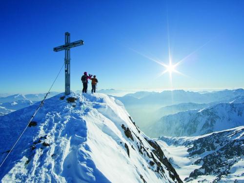 two people standing on top of a mountain with a cross at Hotel Neue Post in Sölden