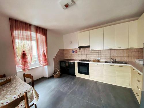 a kitchen with white cabinets and a table and a window at Casa vacanze Da Bianca in Castelfondo