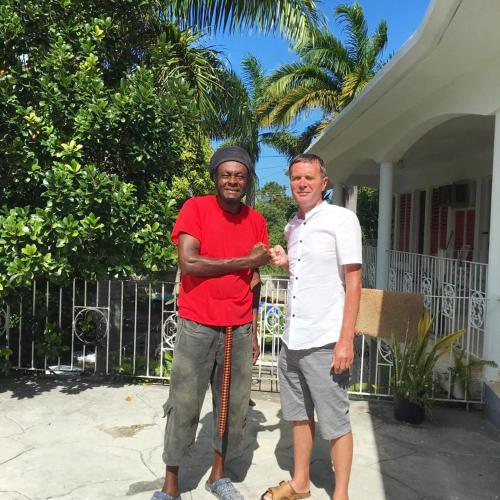 two men standing in front of a house at African Symbol Guest House in Montego Bay