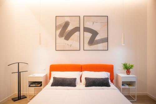 una camera da letto con un letto arancione con tre immagini sul muro di Appartamento Elise a Siderno Marina