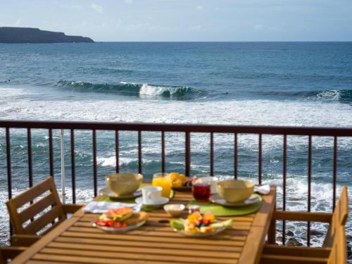 a table with food on top of a balcony overlooking the ocean at Giraud II - Beachfront - Pool - 46 m2 Terrace in Santa Maria de Guia de Gran Canaria