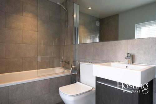 La salle de bains est pourvue d'un lavabo, de toilettes et d'une baignoire. dans l'établissement Modern Luxury Apartment In The Heart of Henley, à Henley-on-Thames
