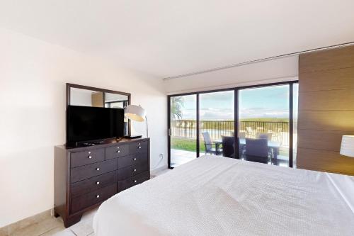 a bedroom with a bed and a television and a balcony at Ocean Vista #102 in South Padre Island