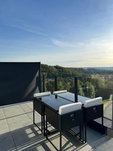 einen Tisch und Stühle auf einem Balkon mit Aussicht in der Unterkunft Liège Luxe & Jacuzzi sous les étoiles in Saint-Nicolas