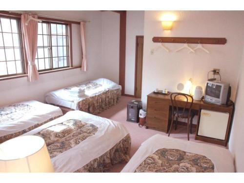 a room with three beds and a desk and a tv at Hotel Montblanc Hakuba - Vacation STAY 49692v in Hakuba