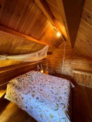 une chambre avec un lit dans une cabane en bois dans l'établissement LES CHALETS DE VANESS' l'Eden, à Digoin