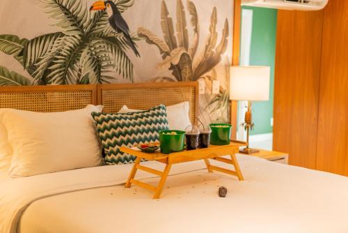 a bed with a table with two green cups on it at Villa do Vale Boutique Hotel in Blumenau
