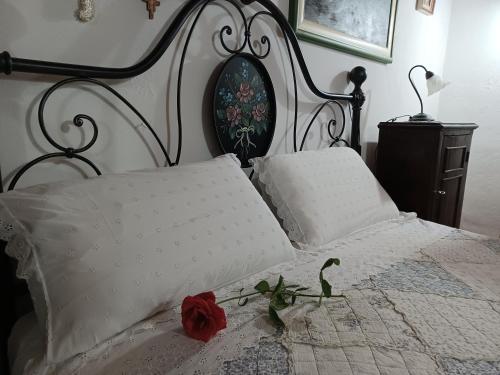 a bed with two pillows and a red rose on it at Il Fontolo in Ponzano Superiore