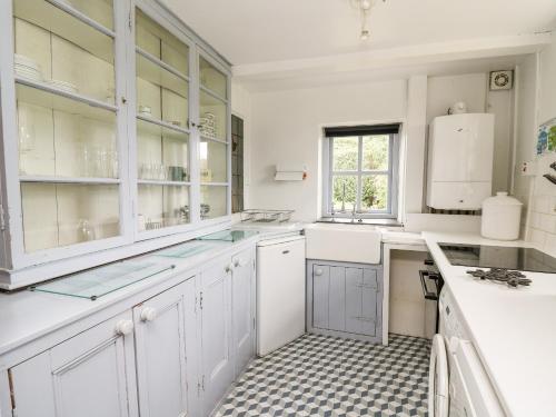 a kitchen with white cabinets and a checkered floor at Red Kite Lodge in Llandeilo
