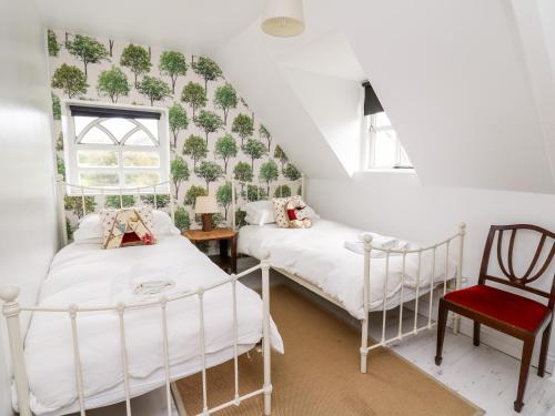 a bedroom with two beds and a red chair at Red Kite Lodge in Llandeilo
