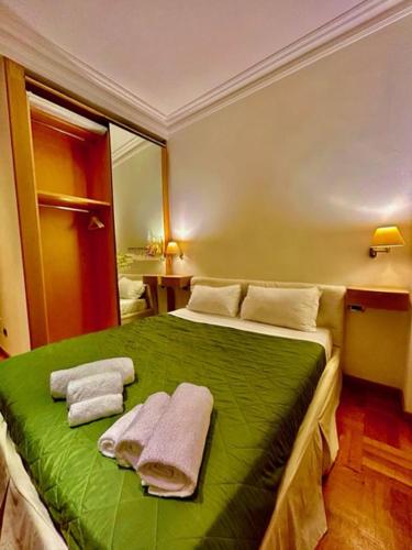 sypialnia z zielonym łóżkiem i ręcznikami w obiekcie Auditorium Maxxi luxury suite Roma w Rzymie