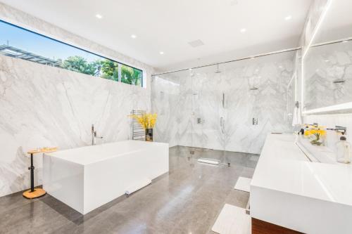 baño con bañera blanca y ventana grande en Sierra Mar, en Los Ángeles