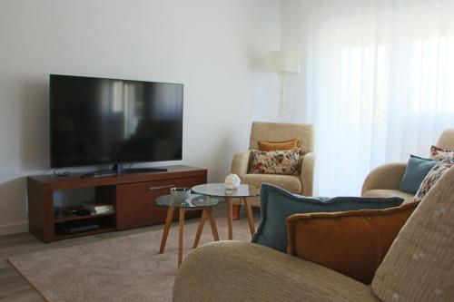 sala de estar con TV, 2 sillas y mesa en ARRUDA LUXURY APARTMENT with AC, en Cascais