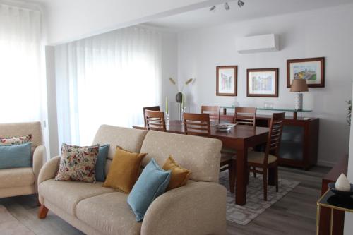 a living room with a couch and a dining room at ARRUDA GARDEN LUXURY APARTMENT with AC in Cascais