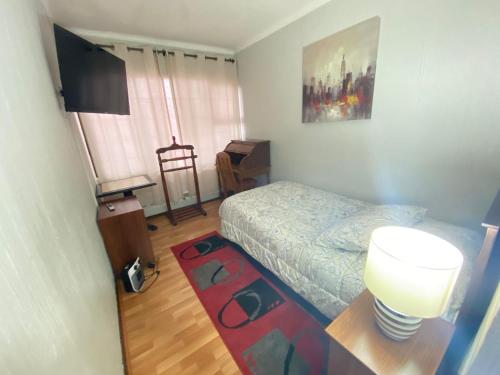 a bedroom with a bed and a table with a lamp at NEW HOTEL CRUZ DEL SUR in Concepción