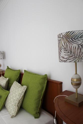 a bed with green pillows and a table with a lamp at ARRUDA GARDEN LUXURY APARTMENT with AC in Cascais
