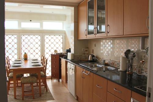 a kitchen with a sink and a table with chairs at ARRUDA GARDEN LUXURY APARTMENT with AC in Cascais