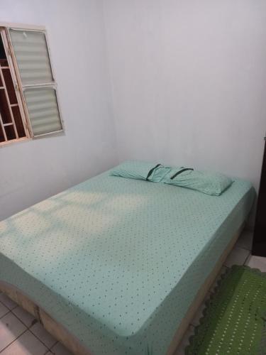 a bed sitting in a room with a window at Quarto privativo em casa de condomínio in Cuiabá