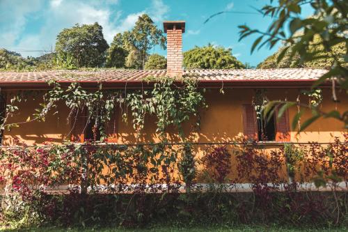 una casa naranja con chimenea de ladrillo y vides en Casa Pedacinho de Céu com banheira de hidromassagem e lareira en São Bento do Sapucaí