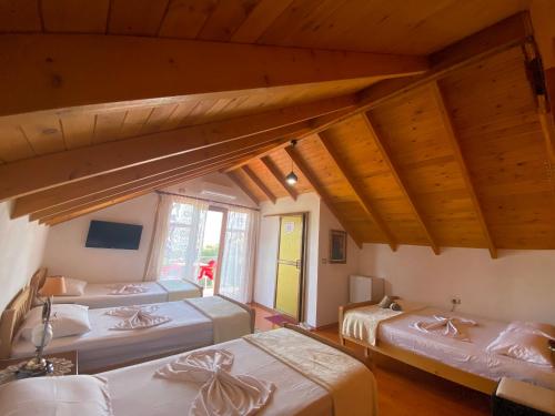 three beds in a room with wooden ceilings at Bixhaku GuestHouse in Gjirokastër