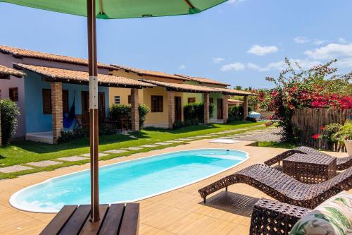 - une piscine avec 2 chaises et un parasol dans l'établissement Condomínio aconchegante a 300mt da Praia de Barra Grande, à Barra Grande