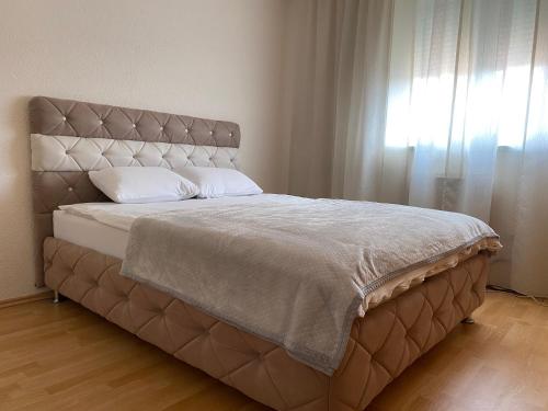 a bed with a large headboard and a window at Apartman MARIJA in Bosanski Šamac