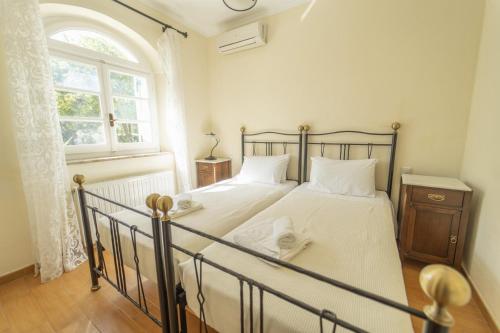 een slaapkamer met een bed met witte lakens en een raam bij Villa Emily in Ágios Stéfanos