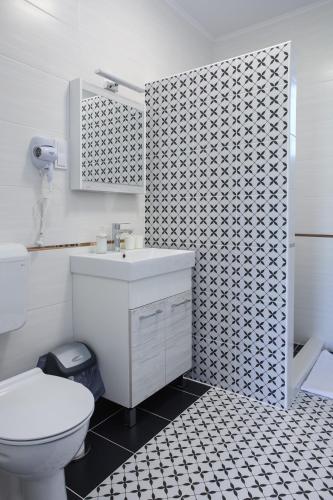 a bathroom with a white toilet and a sink at Cigándi Családi Panzió in Cigánd