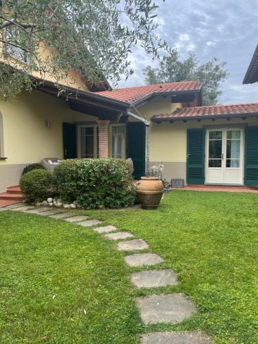 una casa con un patio verde con un camino de piedra en Your house by the sea en Marina di Pietrasanta