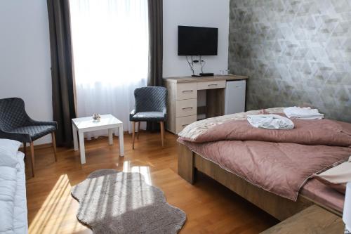 um quarto com uma cama, uma secretária e cadeiras em Cigándi Családi Panzió em Cigánd