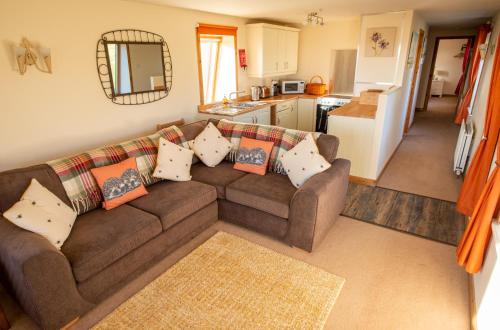 sala de estar con sofá marrón y cocina en The High Croft en Rogart