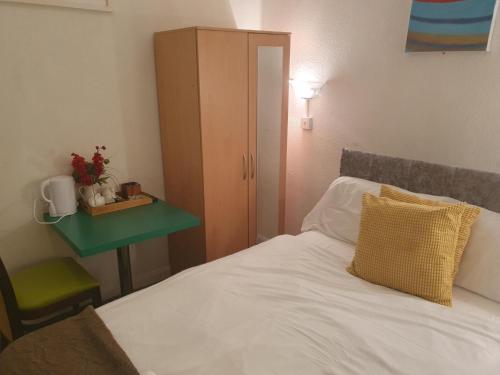 伯明罕的住宿－Ababeel Hotel，一间卧室配有一张带绿桌和橱柜的床。