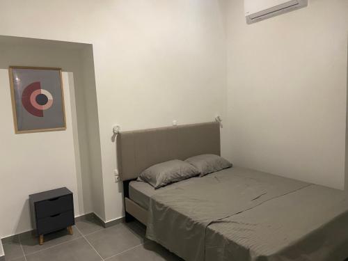 a small bedroom with a bed and a night stand at Leo's Apartments in Koropi