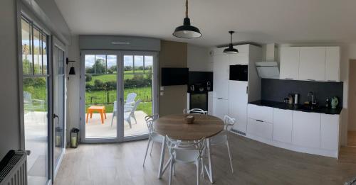 une cuisine avec une table et des chaises dans une pièce dans l'établissement L'Olivier en Baie, T3 de standing avec jardin, vue baie, parking privé, à Saint-Valery-sur-Somme