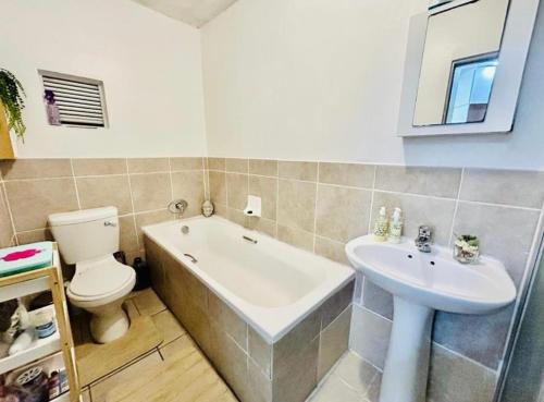 a bathroom with a tub and a toilet and a sink at Makwande Self-Catering Apartment in Durban