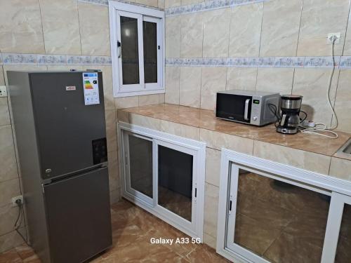 a kitchen with a counter with a microwave and a refrigerator at VILLE FRANCE PATOIS in Thiès