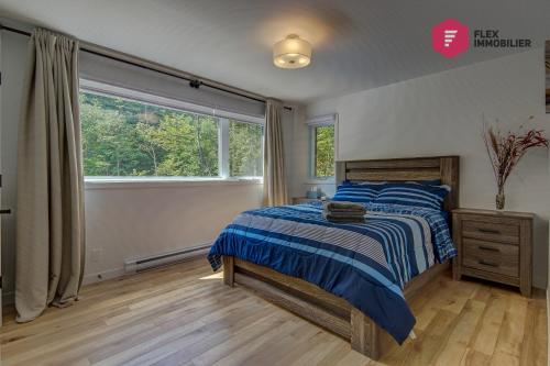 a bedroom with a bed and a large window at L'Arbre de la Montagne Orford - Ski Hiking Bicking Golf Beaches in Magog-Orford