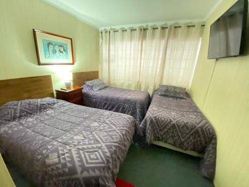 a hotel room with two beds and a television at NEW HOTEL CRUZ DEL SUR in Concepción
