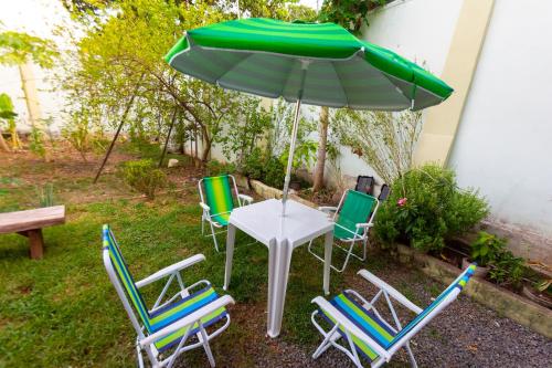 a table and chairs with a green umbrella at HOSTEL DIKASA in Cuiabá