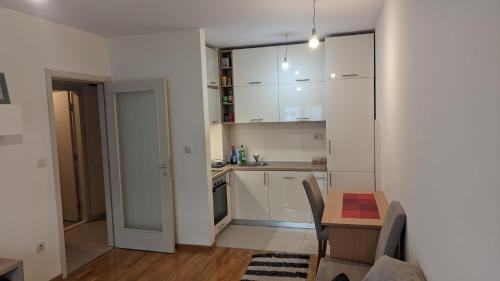 a kitchen with white cabinets and a table and a dining room at Guest House Mikeli (BESPL. DORUCAK)-(FREE BREAKFAST) in Podgorica
