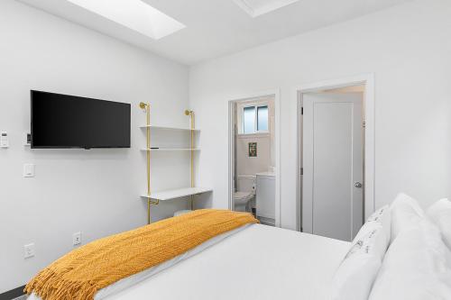 a white bedroom with a bed and a flat screen tv at Yoda's Swamp Suite in Seattle