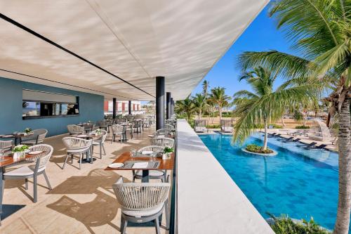 um pátio exterior com mesas e cadeiras e uma piscina em Live Aqua Punta Cana - All Inclusive - Adults Only em Punta Cana