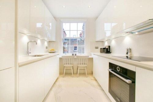 cocina blanca con fregadero y lavavajillas en Prime Mayfair Pied De Terre Sleeps 6 Top Floor en Londres