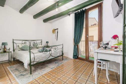 a bedroom with a bed and a desk and a window at La Casa Vella EL BEDORC in Piera