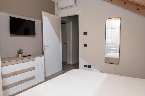 a white bedroom with a tv and a mirror at Affittacamere Bar Leo in Pregnana Milanese