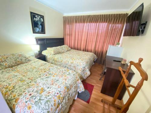 a hotel room with two beds and a desk at NEW HOTEL CRUZ DEL SUR in Concepción